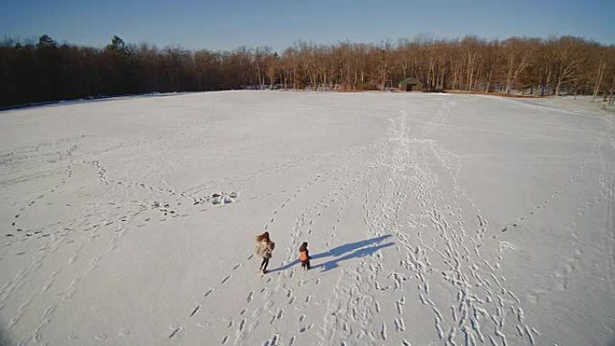 十几岁的女孩和小男孩在雪地上奔跑。慢动作航拍镜头。美国宾夕法尼亚州波科诺斯