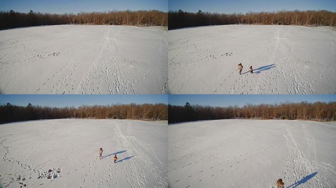 十几岁的女孩和小男孩在雪地上奔跑。慢动作航拍镜头。美国宾夕法尼亚州波科诺斯