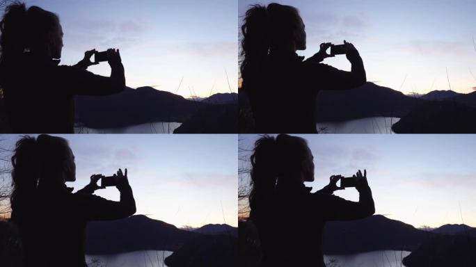 湖边视点的年轻女子使用智能手机拍照