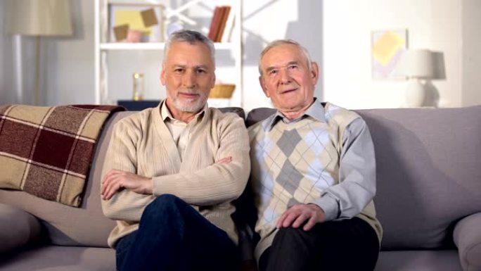 两个老朋友坐在家里的沙发上，看着镜头，社会支持