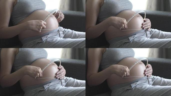孕妇通过耳机为未出生的婴儿播放音乐