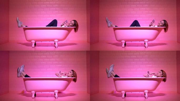在粉红色的浴缸里使用手机的女人