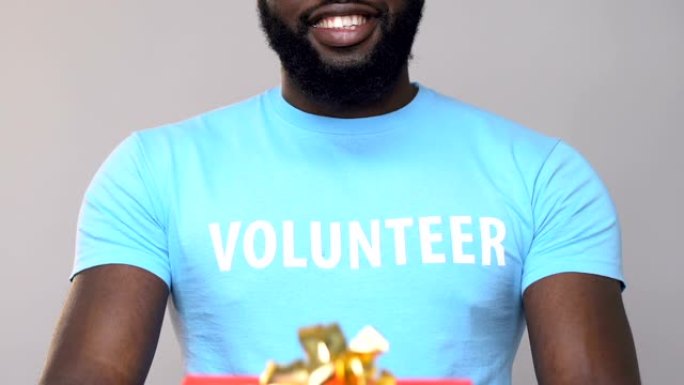 微笑的非洲裔美国志愿者拿着纸板礼盒，援助慈善机构