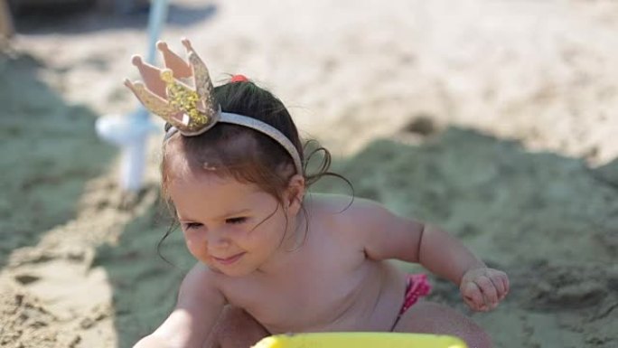 女婴在水边的沙子里玩耍