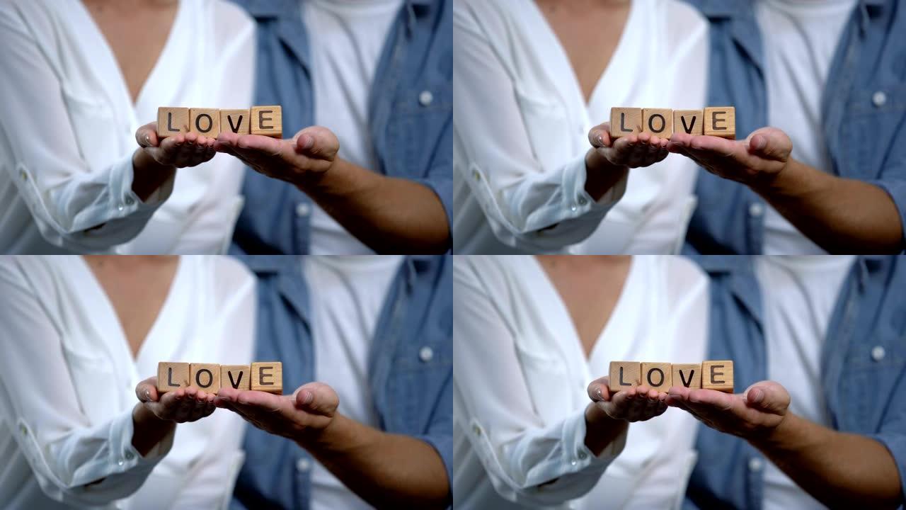 木方块上手持爱情字的男女，家庭关系概念