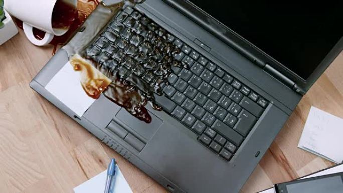 SLO MO LD女性的手打翻一杯茶并将其洒在笔记本电脑上