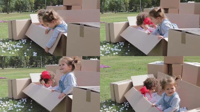 两个快乐的多元文化婴儿在纸箱里玩耍，一个婴儿变得紧张，想出去，玩完了