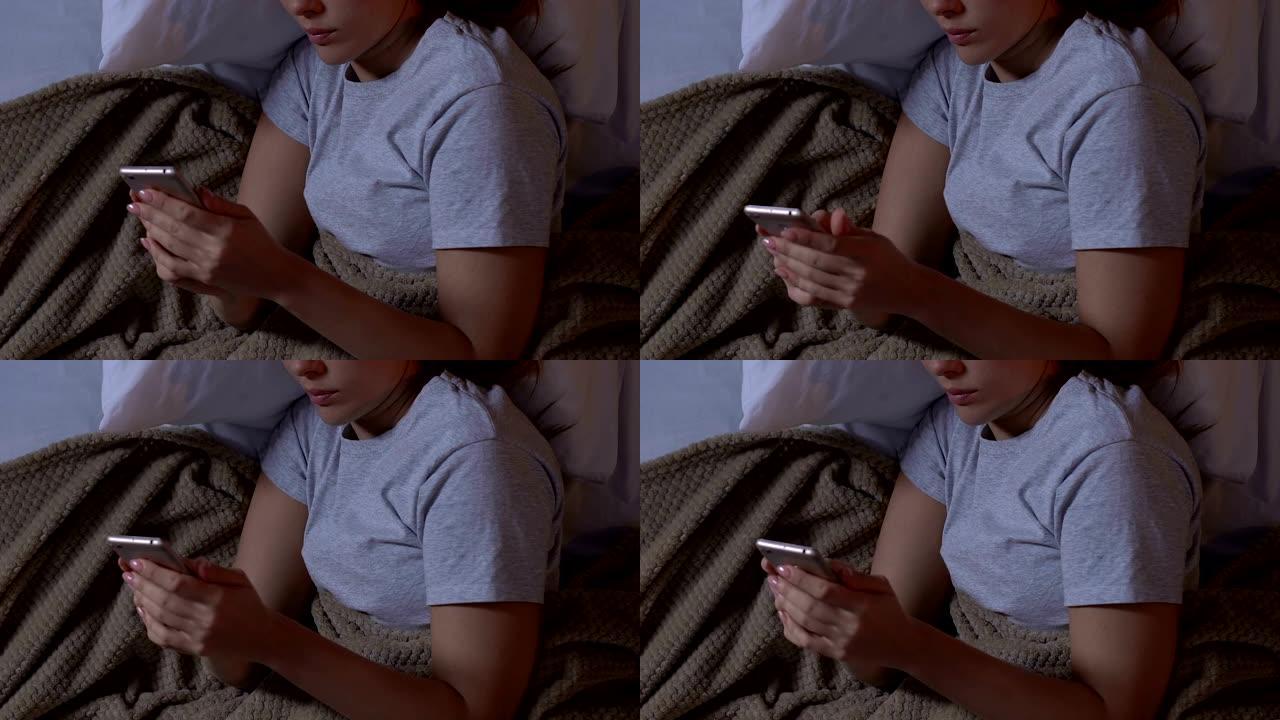 女人在床上使用智能手机，在社交网络中聊天，小工具成瘾