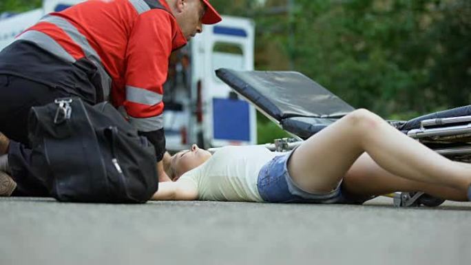 救护车服务人员使用担架将昏迷的女孩送往救护车