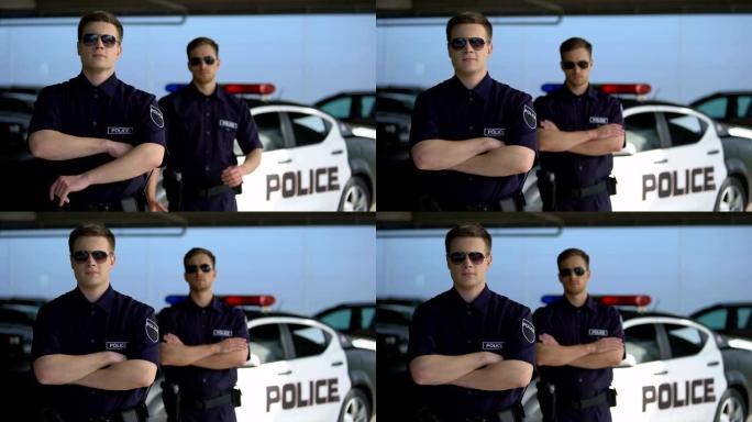 戴着太阳镜的男警官双手交叉站在警车上