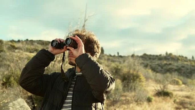 年轻人，25岁的旅行潮人，从优胜美地国家公园魔鬼舞池附近的高架岩石点用双筒望远镜观察自然