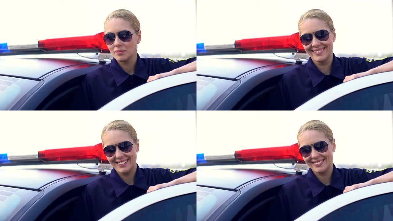 戴着墨镜的女警微笑着，看着相机，站在巡逻车附近