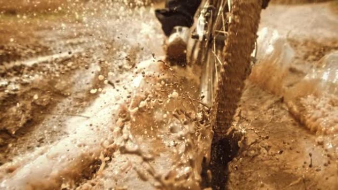 超级慢动作: 追踪骑自行车的人在泥泞中骑行