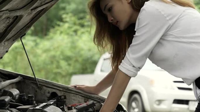 美丽的亚洲女孩看发动机她的车坏了