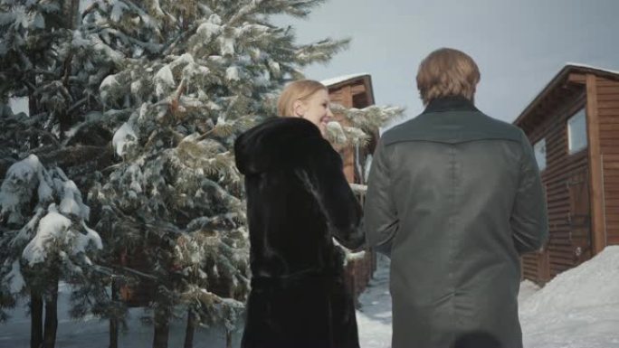 穿着暖和外套的男人和女人在木屋附近的雪场里走向白马的男性形象。
