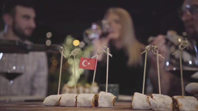 在现代土耳其餐厅的餐桌旁，两个男人和女人用红酒叮当作响。