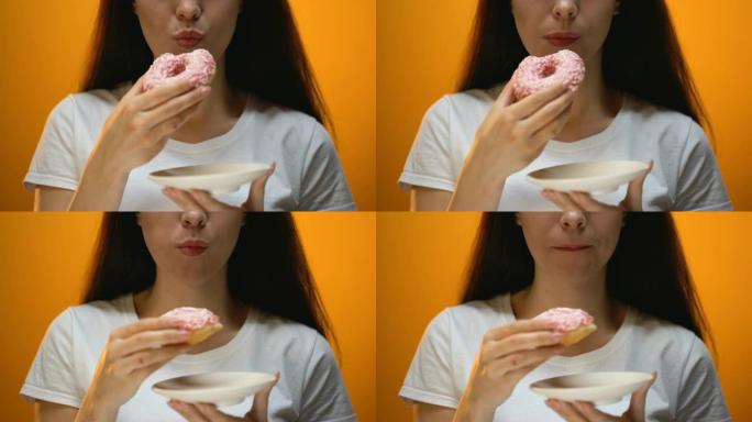 女孩吃甜甜圈，对相机微笑，对甜食上瘾，患糖尿病的风险