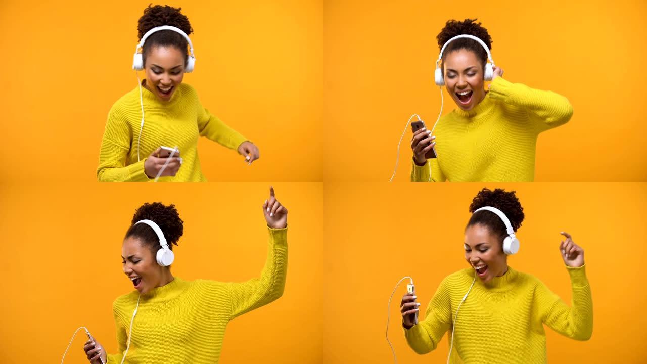 快乐的非洲裔美国妇女在耳机享受最喜欢的歌曲在广播应用程序
