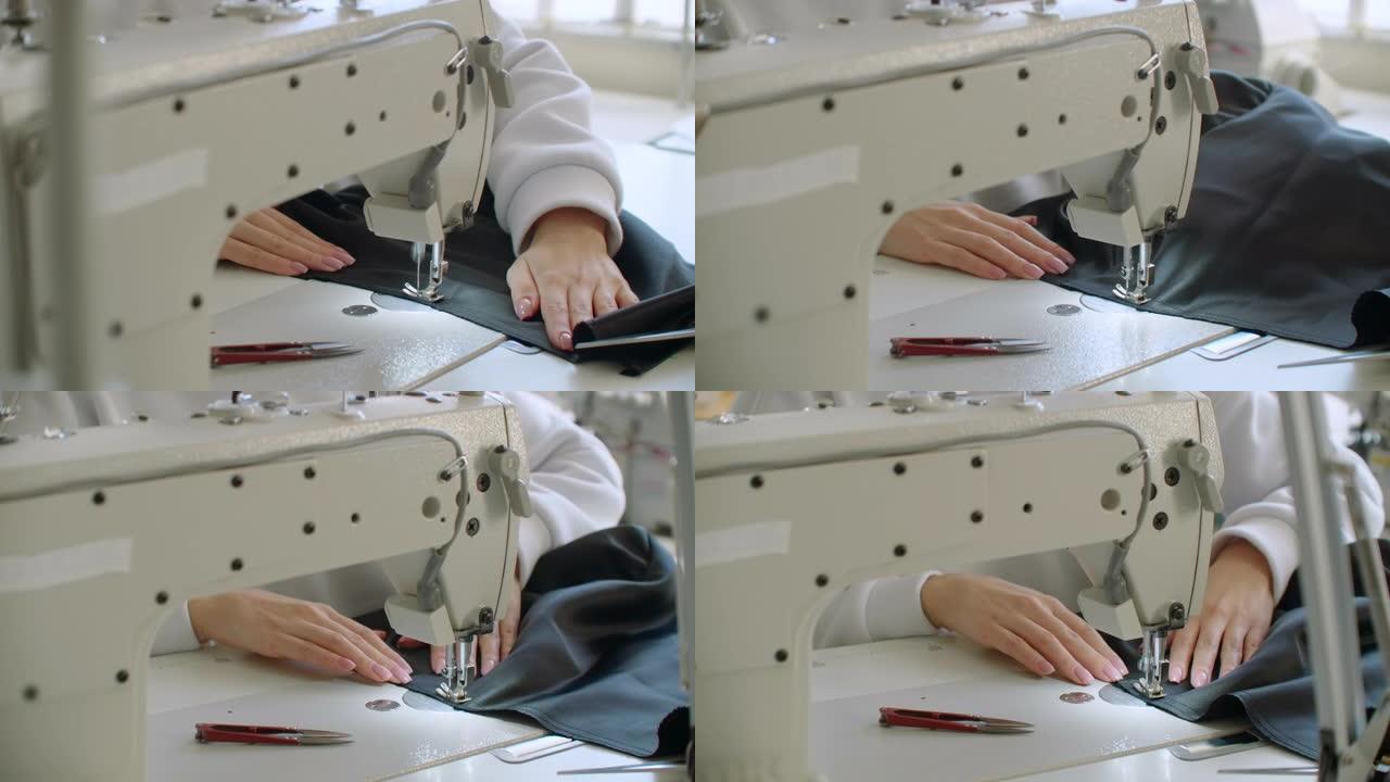 一只女性的手推动材料通过缝纫机。