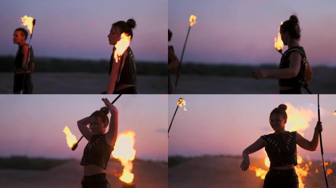 日落时分，在沙滩上放火的妇女跳舞，并以慢动作向美丽的天空展示技巧。