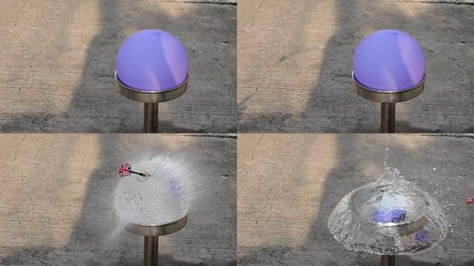 飞镖刺穿紫色水气球的慢动作