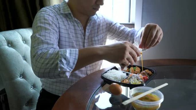 穿着工作服的男人在办公室的午休时间吃日本食物。