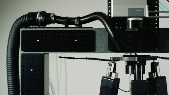 四十多岁的高加索工程师戴着护眼装置监督激光加工超快系统在室内制造设施中的液压机器人腿上倾斜和旋转