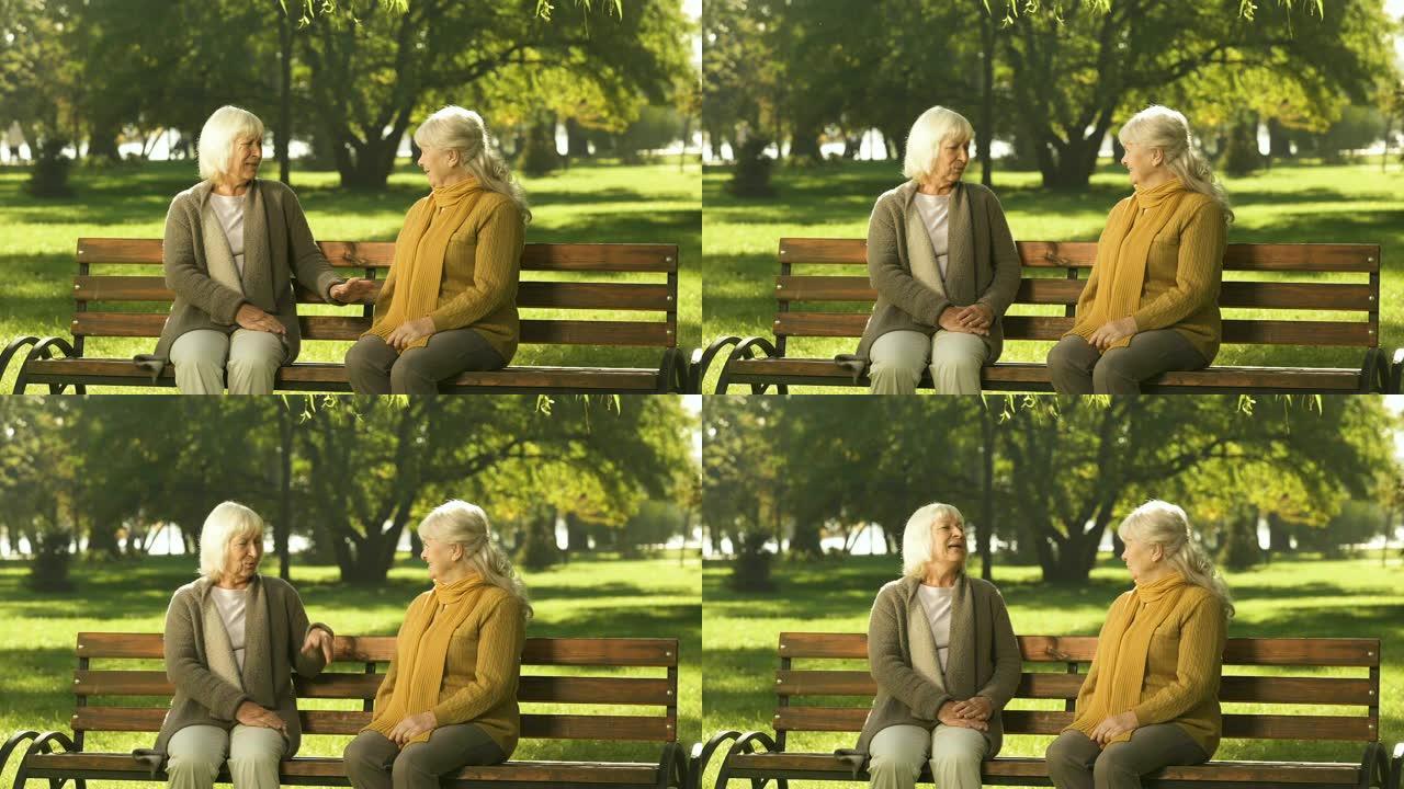 两位祖母交谈，友好地坐在公园的长凳上，古老的黄金岁月