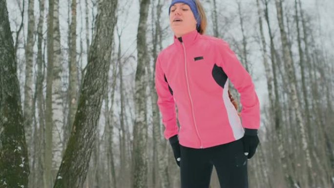 一个年轻的女人在冬天的森林里慢跑，累了，停下来喘口气。他恢复了体力，克服了乏力，继续奔跑。坚持不懈，