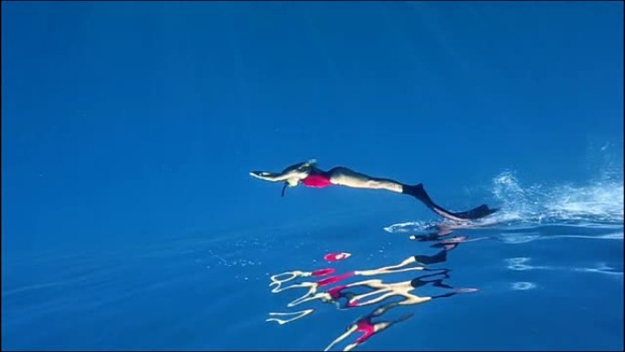 在蓝色水中潜水的自由潜水者