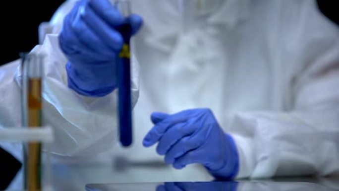 有毒的实验室工作人员展示了带有生物危害液体的试管，病毒菌株
