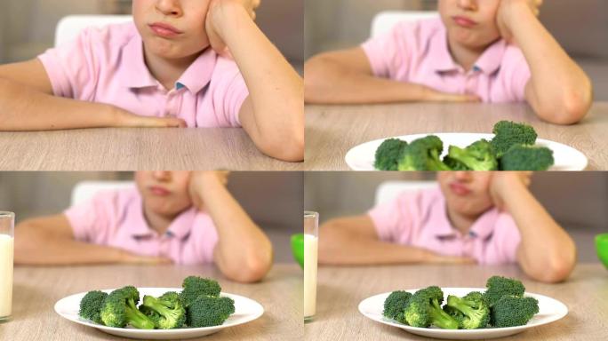 心烦意乱的男孩厌恶地看着西兰花，拒绝进食，素食主义者的生活方式