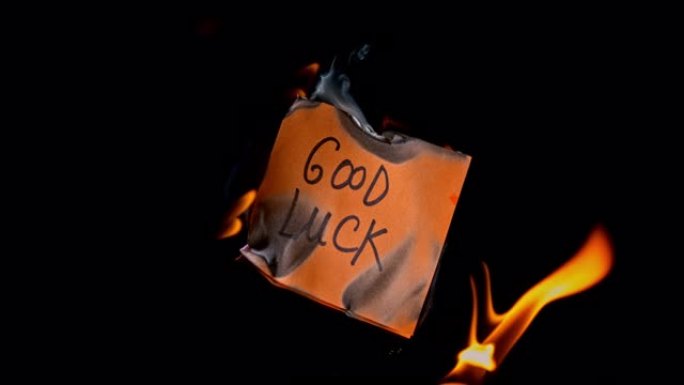SLO MO LD橙色纸片，上面刻有 “好运” 字样，在火焰中燃烧
