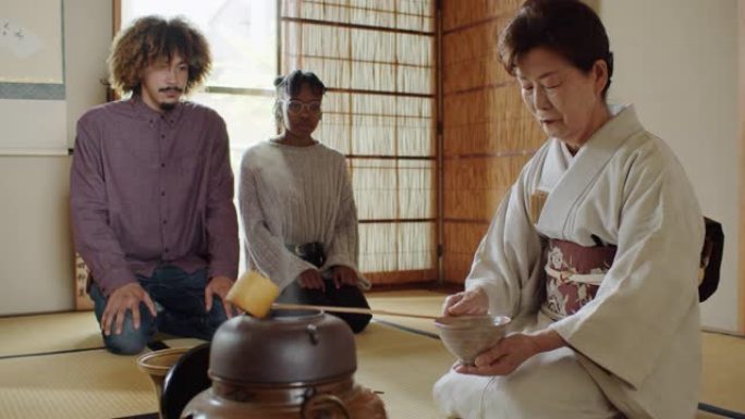 外国游客在传统的日本仪式上观察女主人喝茶