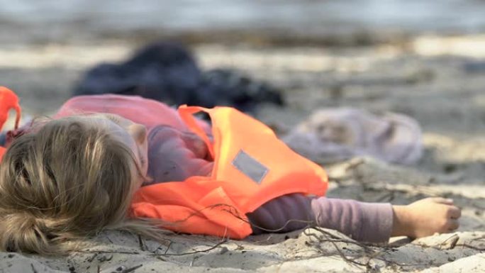 身穿救生衣的女孩躺在没有意识的海岸上，自然灾害受害者