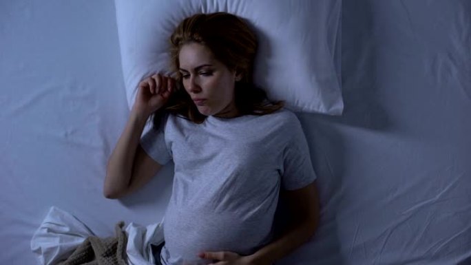 女性孕妇躺在床上感觉恶心，孕吐，怀孕健康