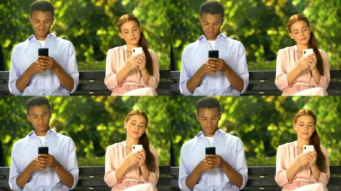男女青少年坐在长凳上，在智能手机上聊天，出现问题