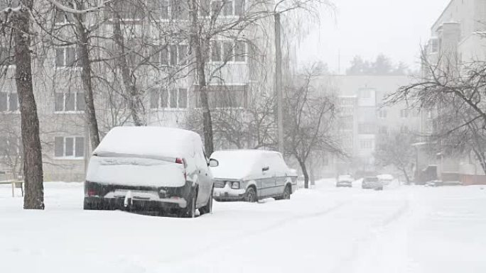 暴风雪和积雪覆盖着停着汽车的街道。