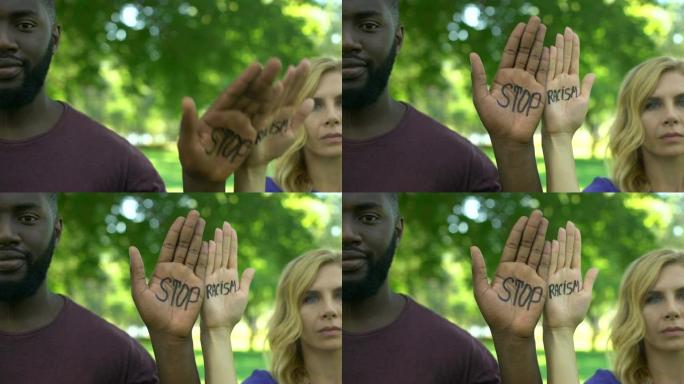 美国黑人男子和白人妇女表现出手掌，并带有停止种族主义短语
