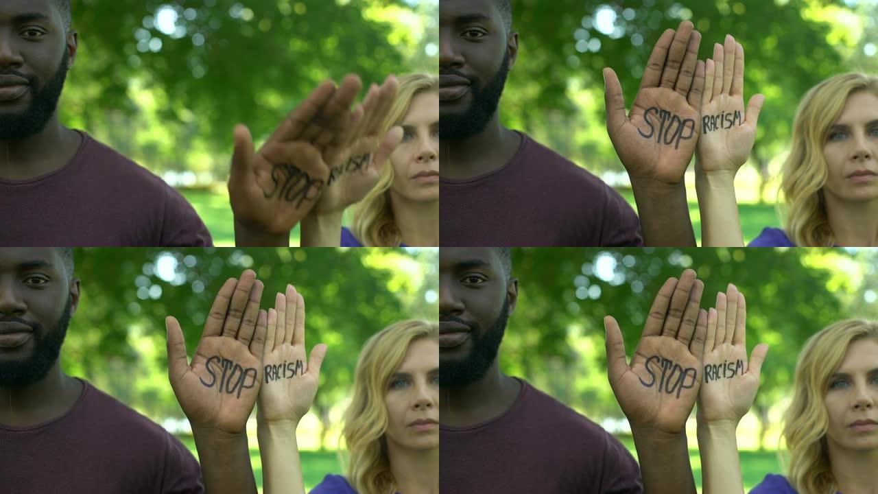 美国黑人男子和白人妇女表现出手掌，并带有停止种族主义短语