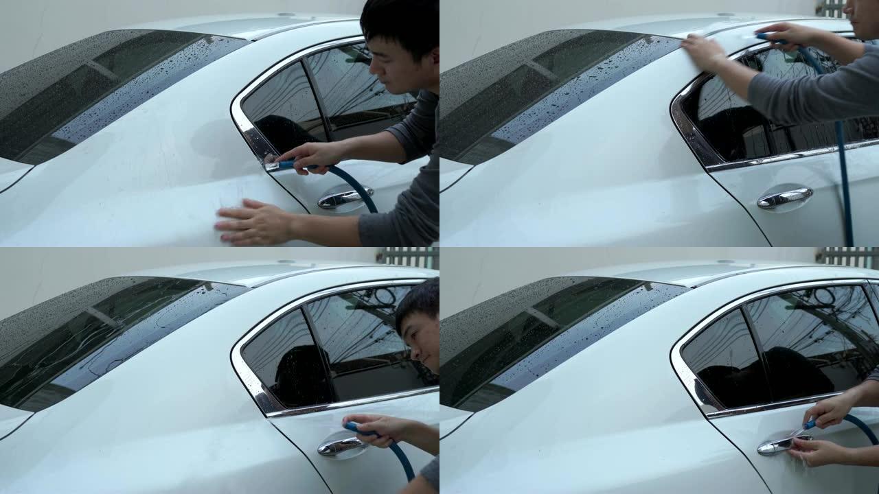 他正在用水清洗白色汽车。