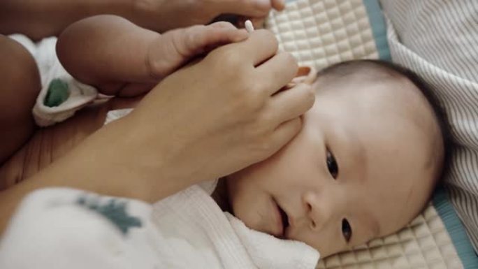 母亲用棉花蕾清洁了刚出生的婴儿的耳朵