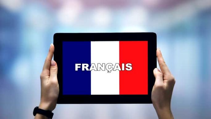 女性手握平板电脑，法语单词反对国旗，在线应用