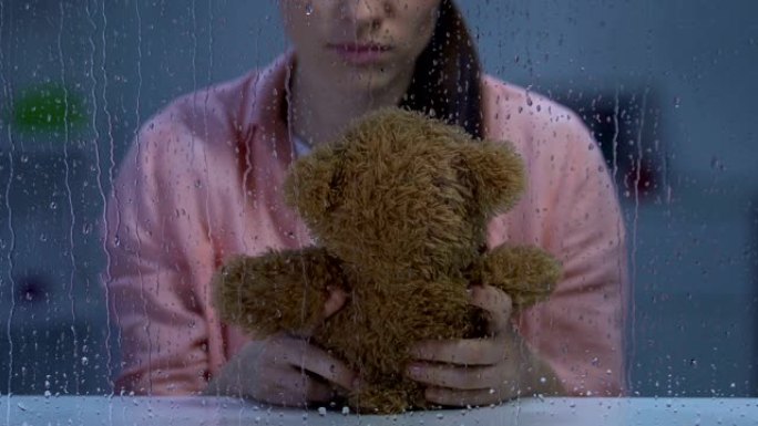 痛苦的女士抱着泰迪熊，失踪的孩子和抑郁症