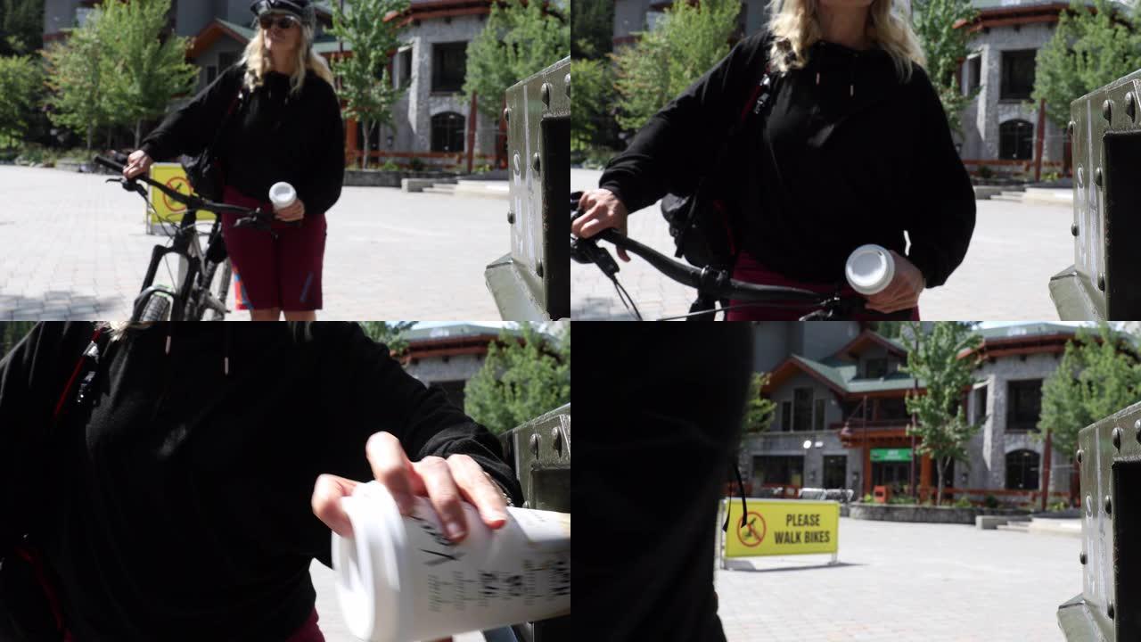 女骑自行车的人将可回收的杯子放在容器中