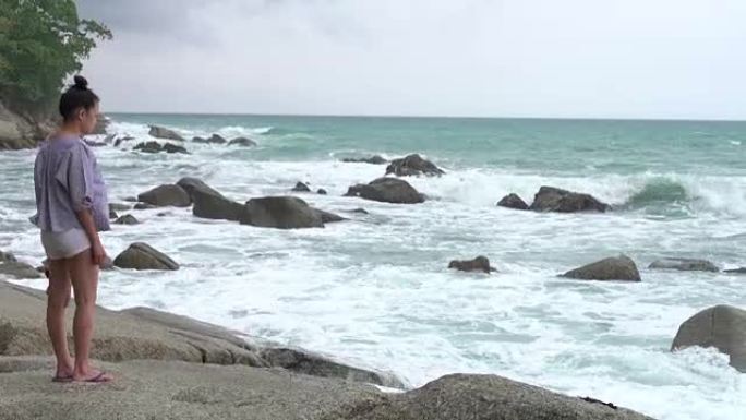 4k: 岩石上的海滩上的女孩受到波浪打击