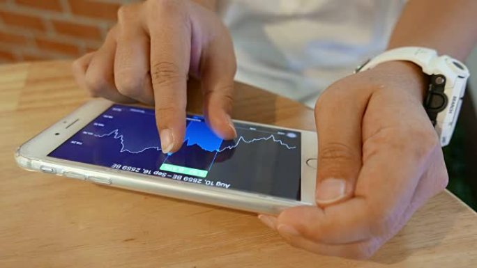 女人检查智能手机上的交易市场图表