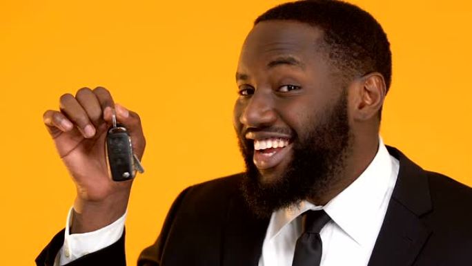 快乐的非裔美国男经理展示汽车钥匙进入相机，租赁服务