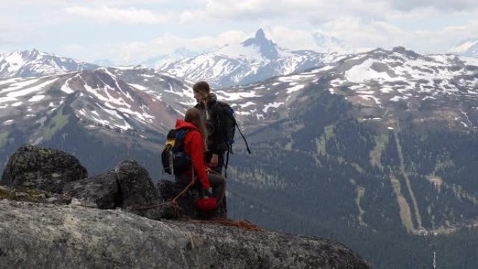 女攀岩者讨论路线，在岩石山顶上准备装备