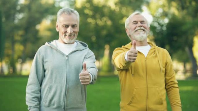 两名穿着运动服的微笑老人表现出竖起大拇指，健康的生活方式
